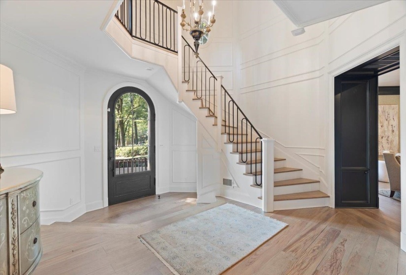 Entryway featuring a decorative wall, stairway, light wood-style floors, a chandelier, and crown molding