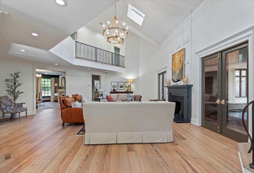 Living area with a chandelier, light wood finished floors, crown molding, high vaulted ceiling, and recessed lighting