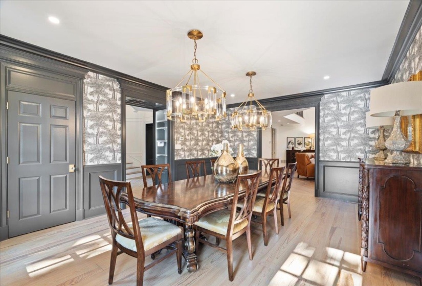 Dining area with a decorative wall, a chandelier, wood finished floors, and crown molding