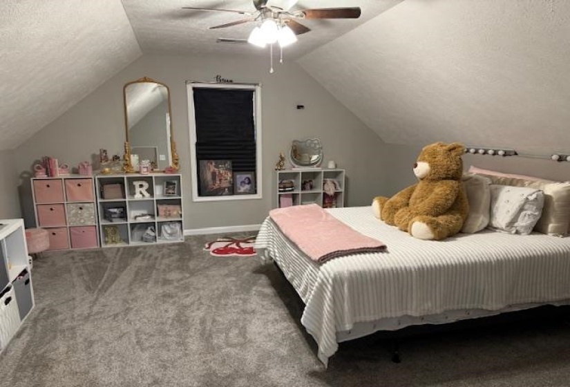 Carpeted bedroom featuring a textured ceiling, lofted ceiling, and a ceiling fan