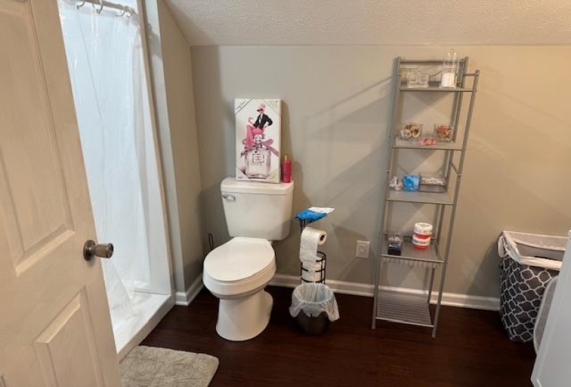 Full bathroom featuring dark wood-style flooring and a textured ceiling