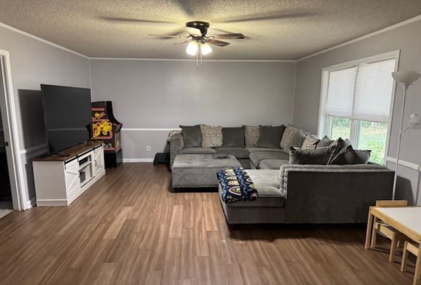 Living area with crown molding, wood finished floors, a textured ceiling, and ceiling fan