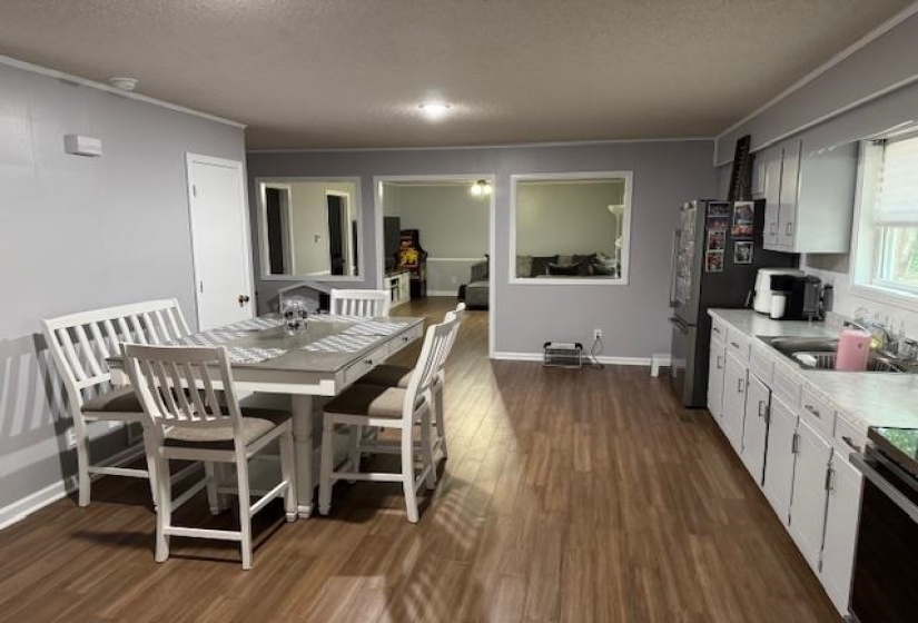Dining space with a textured ceiling, crown molding, and dark wood finished floors