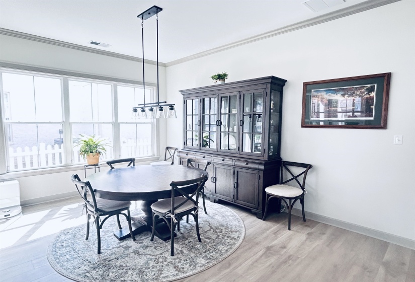 Dining room with ornamental molding and light wood-style flooring