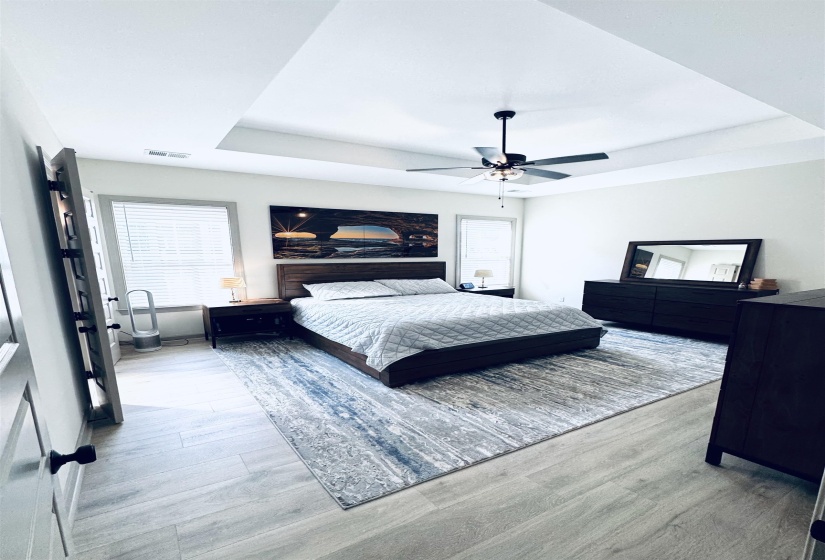 Bedroom with a tray ceiling, light wood-style floors, and ceiling fan