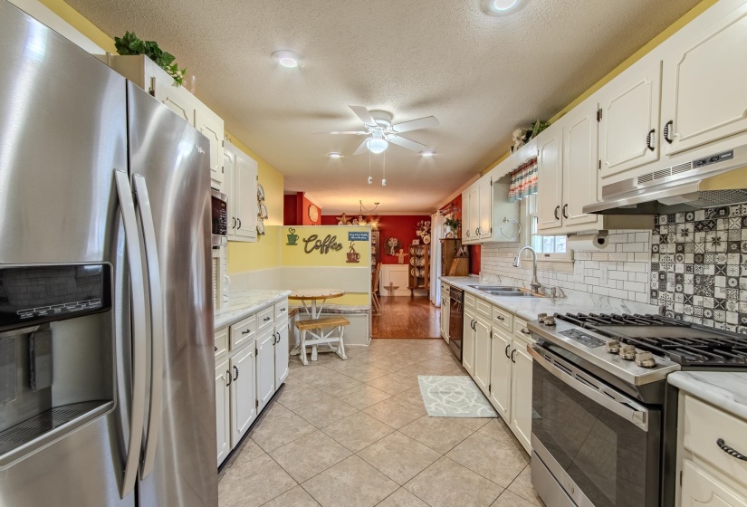 Kitchen featuring stainless steel appliances, light countertops, tasteful backsplash, light tile patterned floors, and a textured ceiling