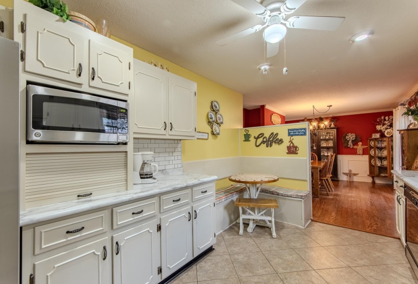 Kitchen with black appliances, white cabinets, light tile patterned flooring, backsplash, and a chandelier