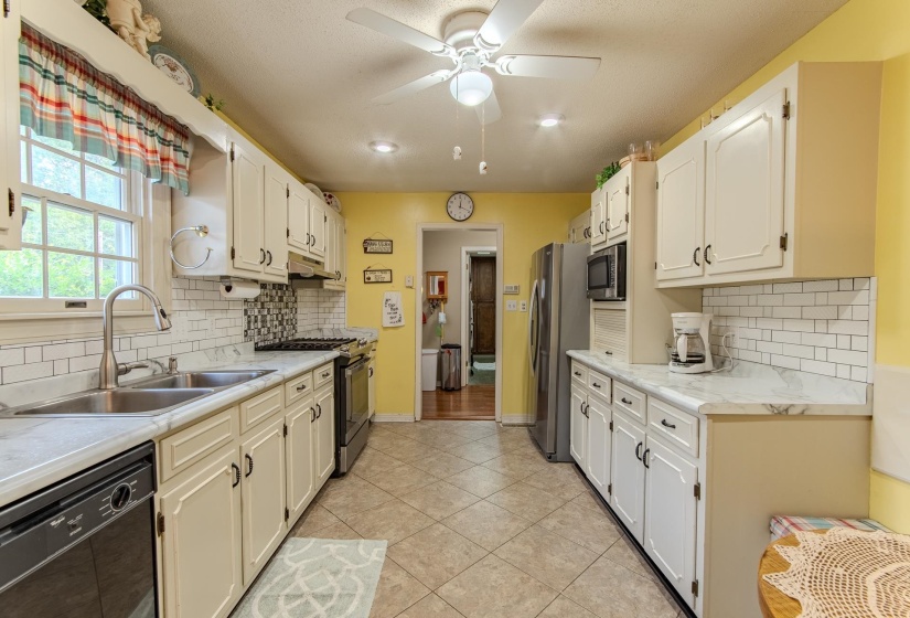 Kitchen featuring light countertops, backsplash, appliances with stainless steel finishes, light tile patterned flooring, and a ceiling fan