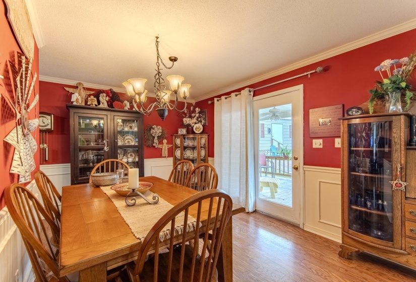 Dining area featuring a wainscoted wall, a decorative wall, ornamental molding, a chandelier, and wood finished floors