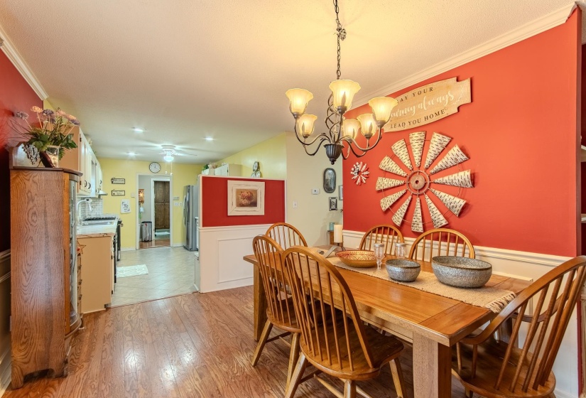 Dining room featuring wainscoting, crown molding, a chandelier, light wood finished floors, and a decorative wall