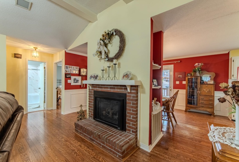 Living room with a fireplace, wainscoting, wood finished floors, a textured ceiling, and a decorative wall