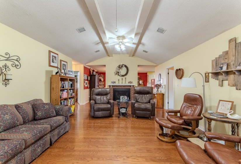 Living room with light wood-style floors, ceiling fan, and a fireplace