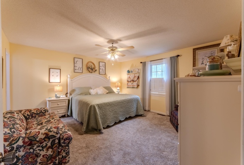 Carpeted bedroom with a textured ceiling and a ceiling fan