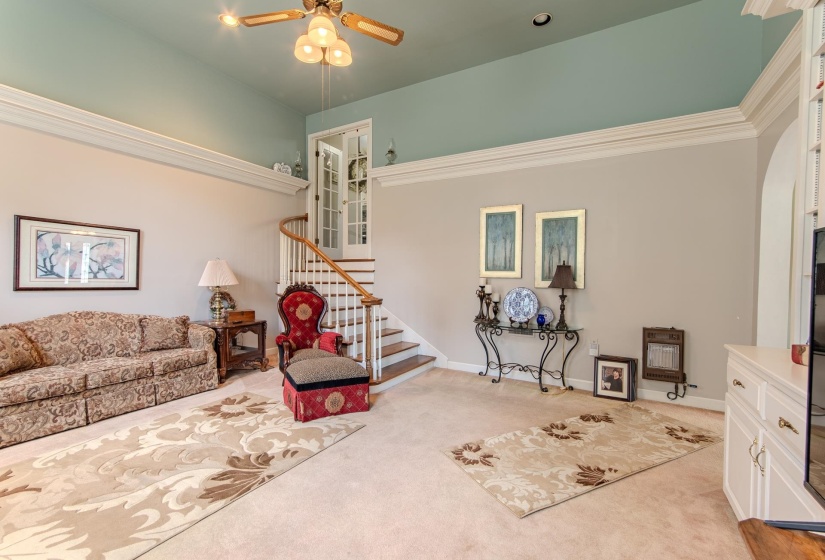 Living room with light carpet, arched walkways, and ceiling fan