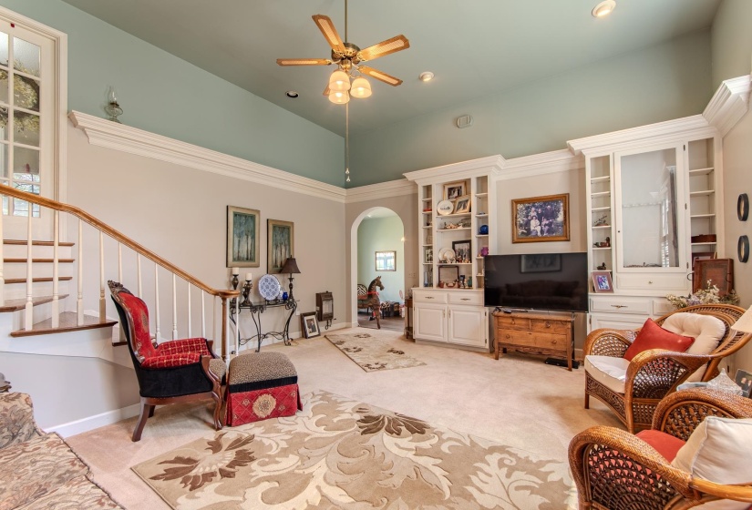 Living room featuring light carpet, arched walkways, stairway, a ceiling fan, and recessed lighting