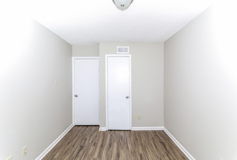 Spare room featuring dark wood-style floors and baseboards
