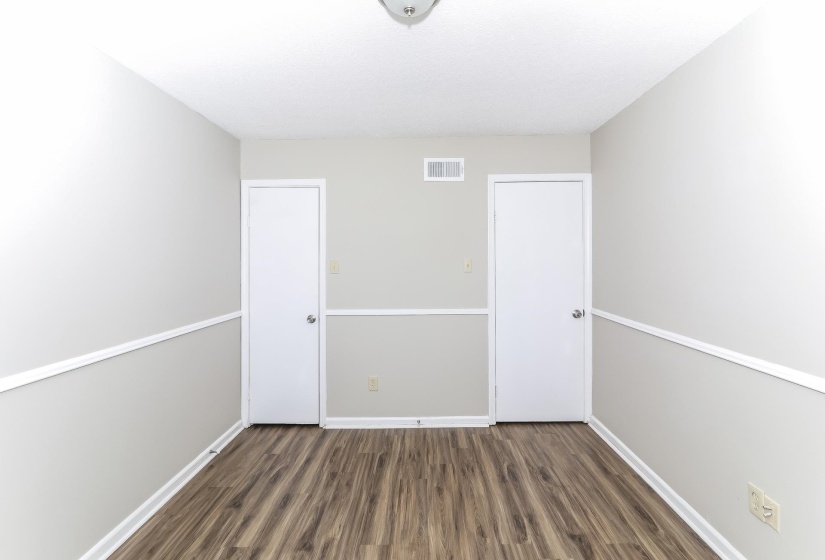 Unfurnished bedroom with dark wood-style floors and baseboards