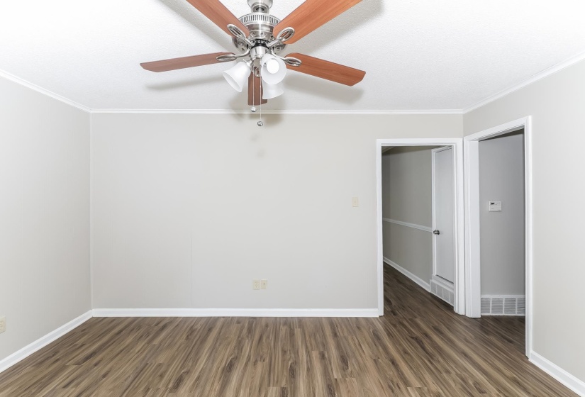 Spare room featuring dark wood-type flooring, crown molding, and a ceiling fan