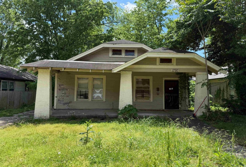 Bungalow featuring brick siding, covered porch, and fence