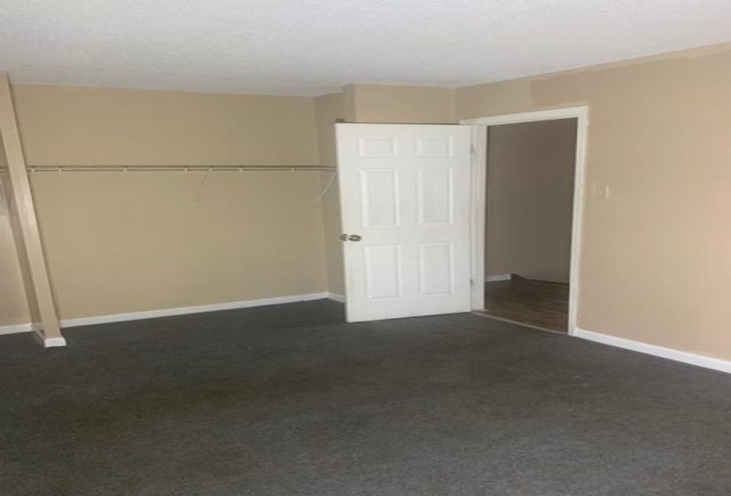 Unfurnished bedroom featuring dark carpet, a closet, and a textured ceiling