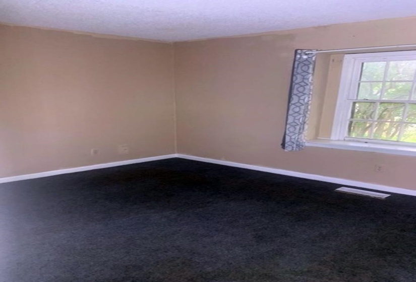 Spare room with dark colored carpet and a textured ceiling