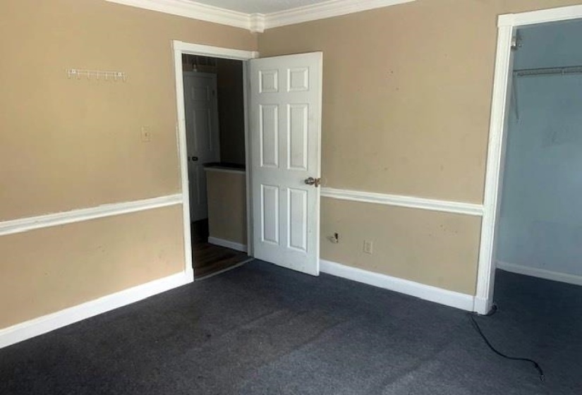 Unfurnished bedroom featuring ornamental molding, dark colored carpet, and a closet