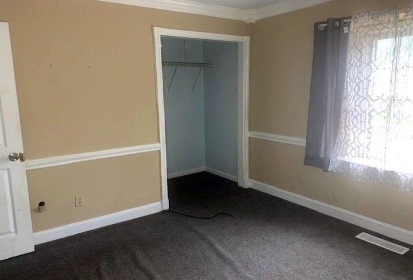 Unfurnished bedroom with crown molding, dark carpet, and a closet