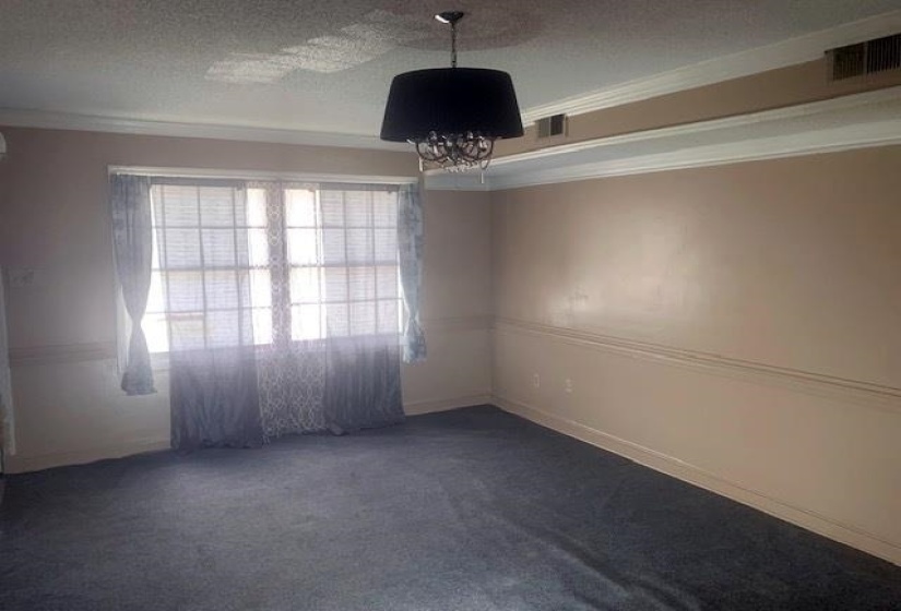 Spare room with dark carpet, a textured ceiling, ornamental molding, and a chandelier