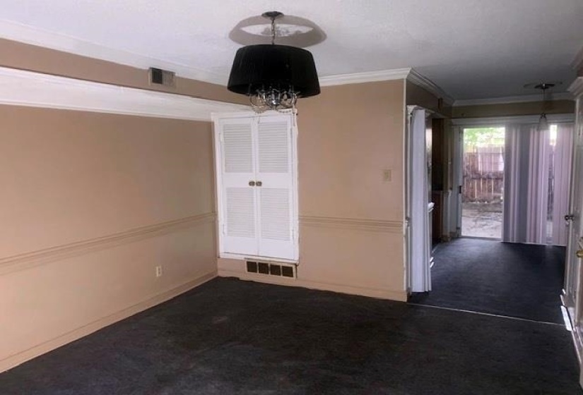 Unfurnished dining area featuring crown molding, dark colored carpet, and a chandelier