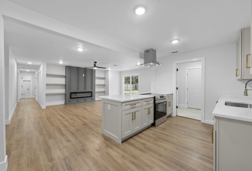 Kitchen featuring stainless steel electric range oven, island range hood, light stone countertops, light wood-type flooring, and recessed lighting