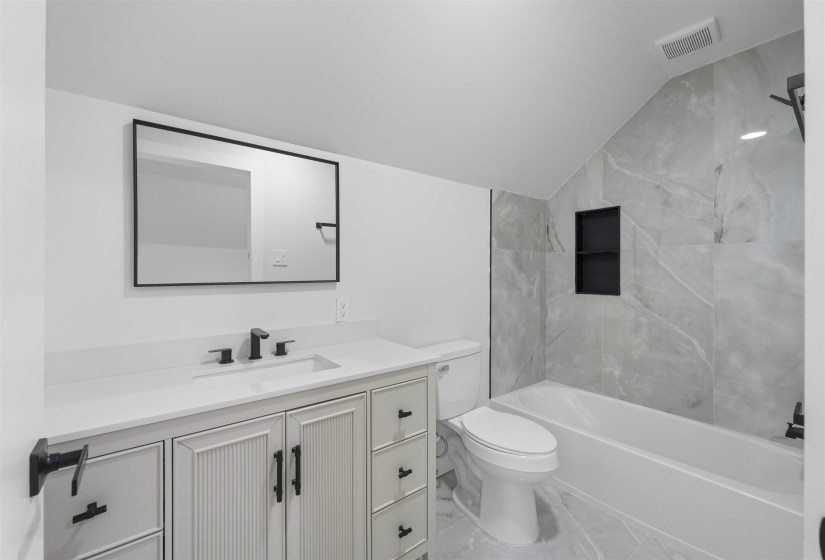 Full bathroom with vanity, shower / washtub combination, lofted ceiling, and light marble finish floors