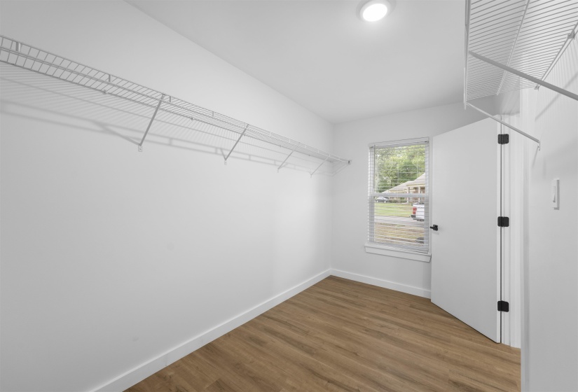 Walk in closet with dark wood finished floors