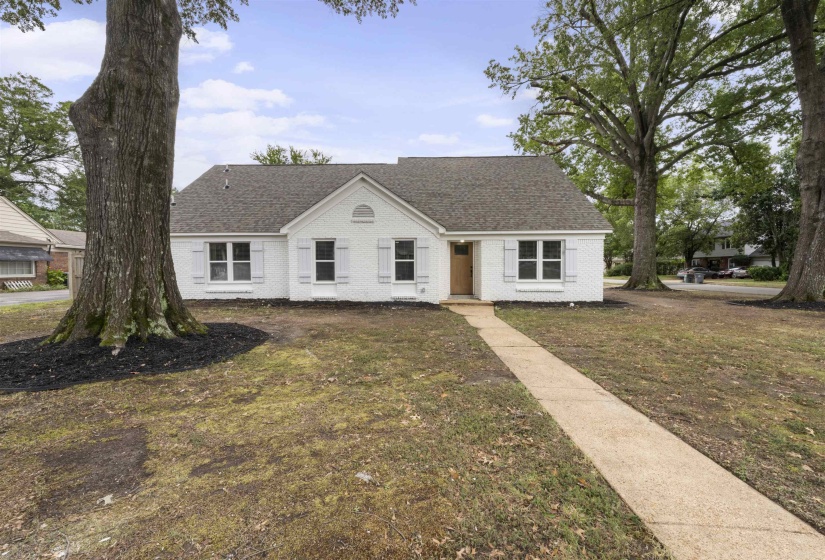 View of front facade with a front lawn, roof with shingles, and brick siding