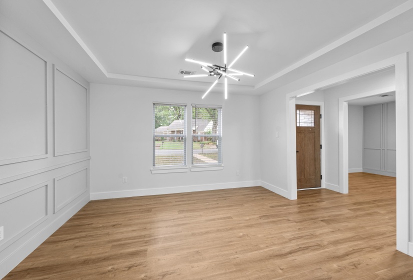 Spare room featuring a chandelier, a tray ceiling, and light wood-style flooring