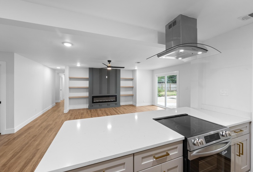Kitchen featuring stainless steel range with electric cooktop, a peninsula, island exhaust hood, light wood-type flooring, and recessed lighting
