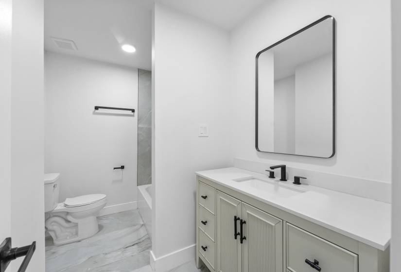 Bathroom with vanity, light marble finish floors, and tub / shower combination