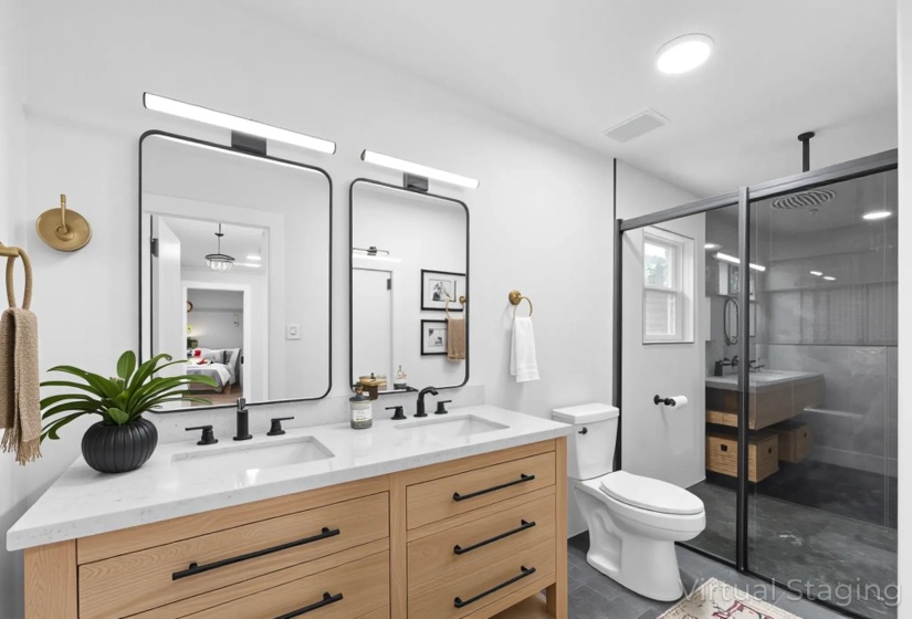 Bathroom featuring a shower stall, double vanity, and connected bathroom