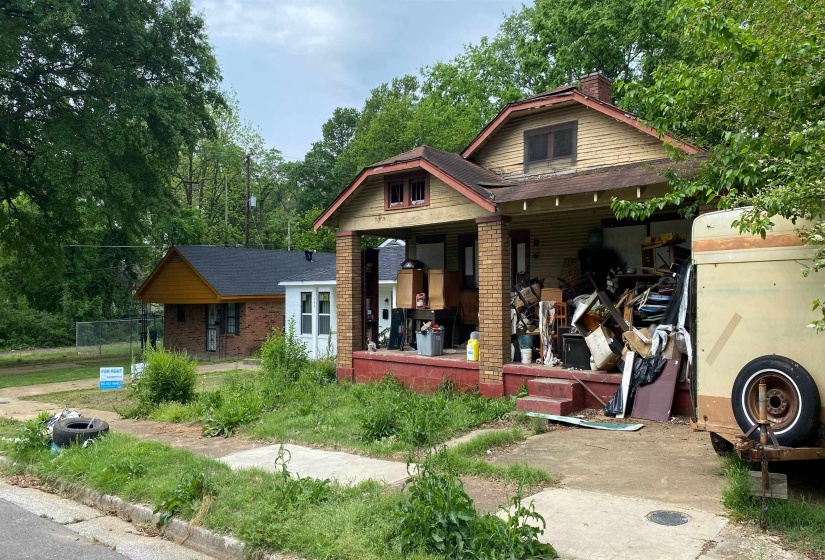 View of front of property with a chimney, brick siding, a porch, and a gambrel roof