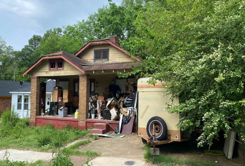 View of front facade featuring a chimney, a porch, and brick siding