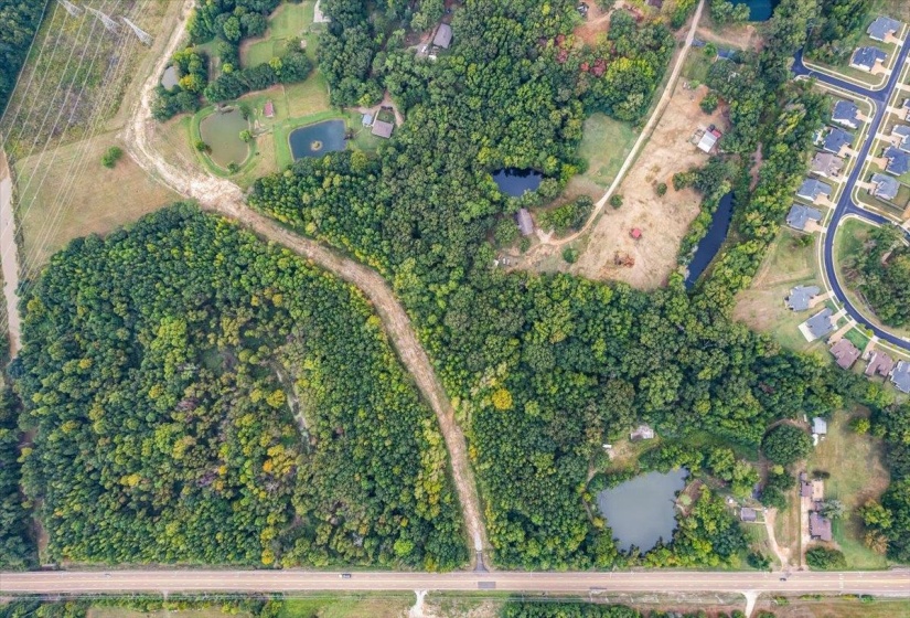 Aerial view of property and surrounding area with a large body of water and a tree filled landscape