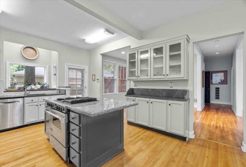 Kitchen with stainless steel appliances, dark stone counters, white cabinets, a center island, and light wood-type flooring
