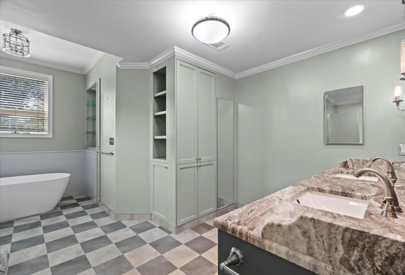 Full bathroom featuring crown molding, double vanity, a soaking tub, built in shelves, and a wainscoted wall
