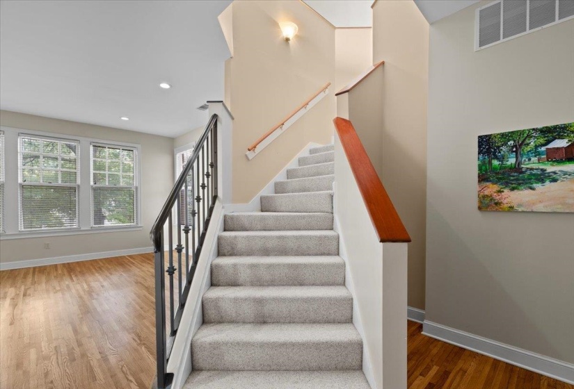 Staircase with wood finished floors and recessed lighting