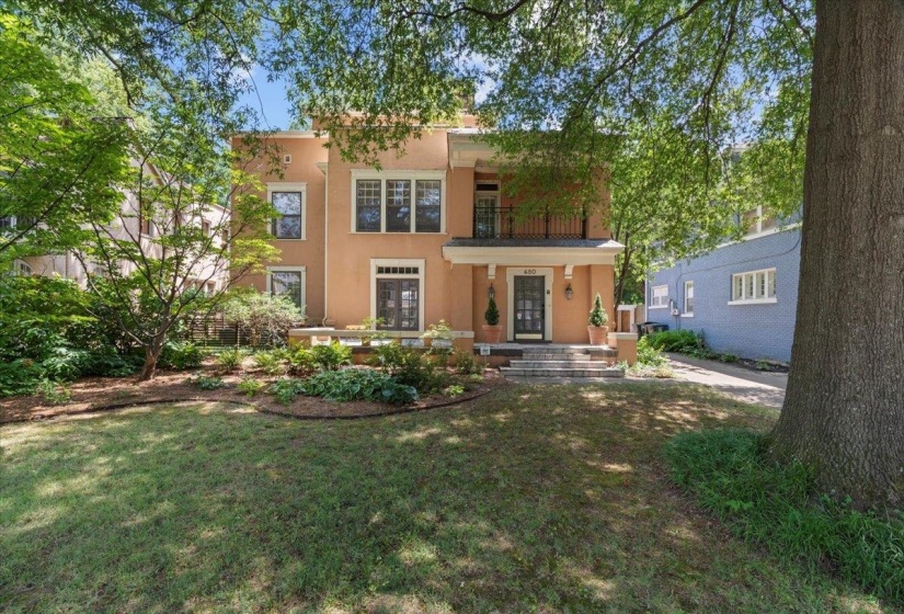 View of front of home featuring a balcony, stucco siding, and a front yard