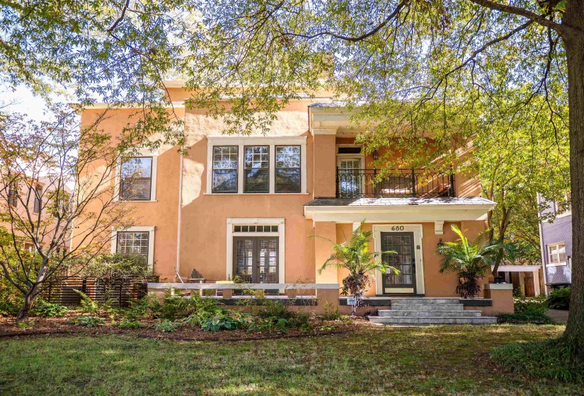 View of front of house featuring a balcony, french doors, and a front yard
