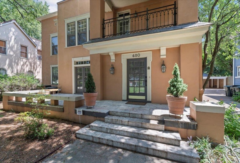 Doorway to property featuring stucco siding, a balcony, and a porch