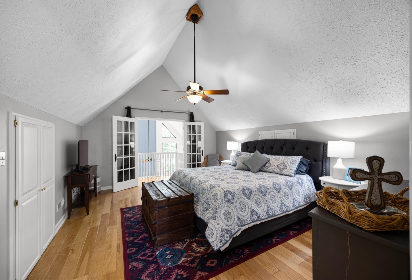 Bedroom with a light wood finished floors, vaulted ceiling, a ceiling fan