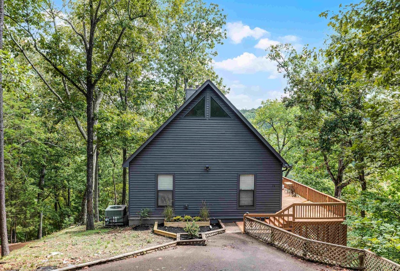 Rear view of house featuring a wooden deck, a vegetable garden, and a view of trees