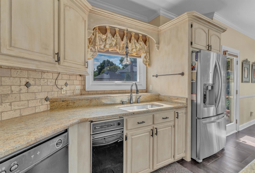 Kitchen featuring cream-toned cabinetry with dark hardware, a light-toned countertop, and a brick-style backsplash
