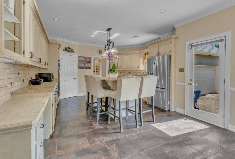 Kitchen featuring an island with seating, stainless steel refrigerator, recessed lighting, tile flooring, and a glass-paneled exterior door